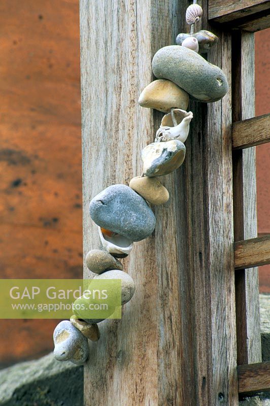 String of sea-worn pebbles wrapped around a wooden post in designer Stephen Woodhams' own roof garden.