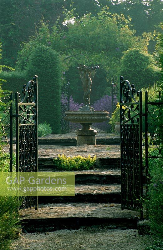 Metal gates and fountain in the walled garden - Eastleach House Garden, Gloucestershire