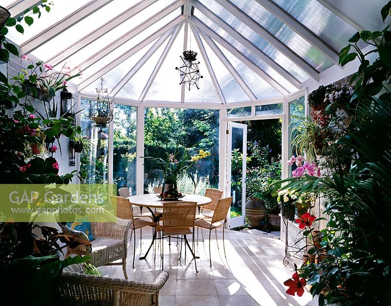 Table and chairs in conservatory with view of garden outside