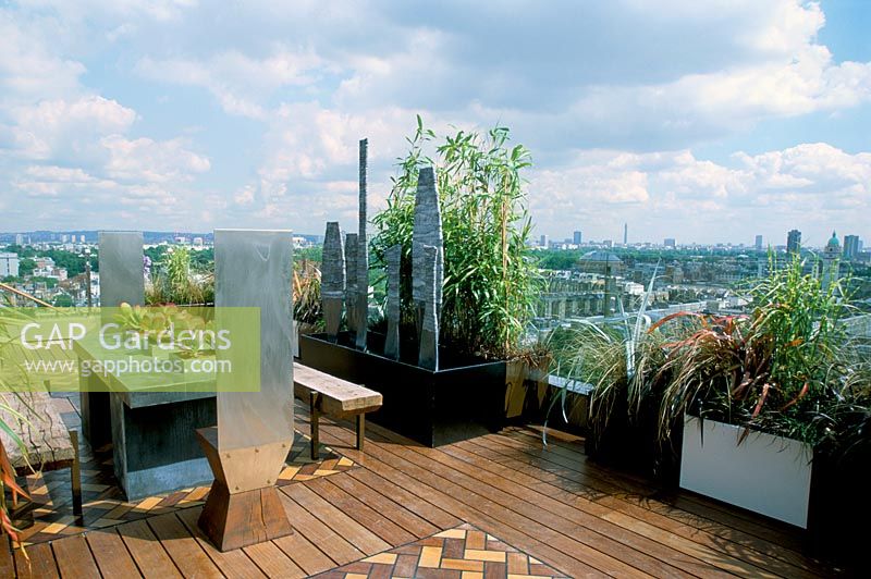 African themed roof terrace with over London - Water feature in black powder-coated container, iroko decking and five lead sculptures by Shaun Brosnan