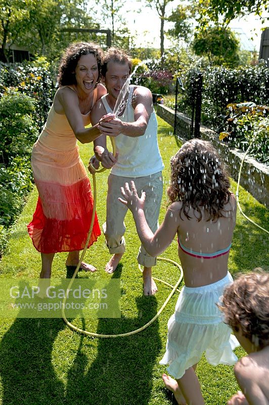 Family playing with hose in garden 
