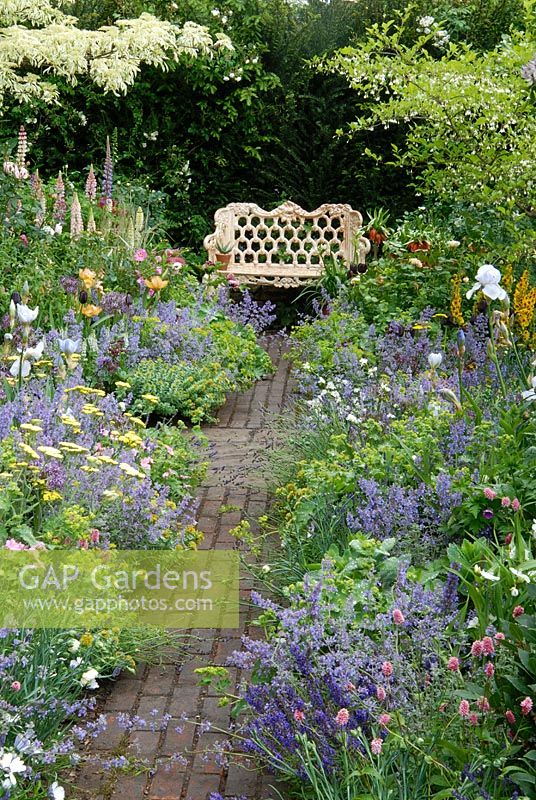 Brick path leading to seat, perennial borders with Nepeta faassenii, Alchemilla mollis and Styrax japonica - The Chris Beardshaw Garden, Chelsea 2007