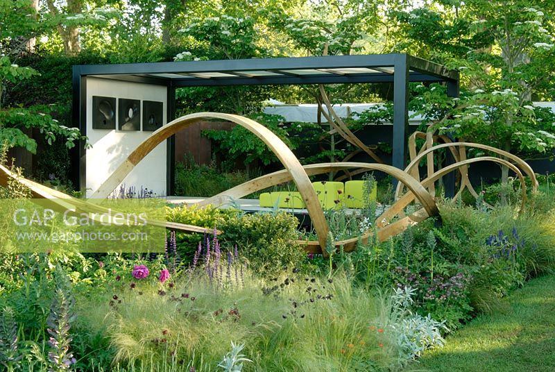 Curved oak ribbons threading through the 'Cancer Research UK Garden', Chelsea 2007 with Japanese-inspired pavillion, perennial planting, and Cornus controversa.
