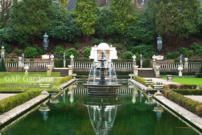 Fountain in large wooded garden in eary spring - The Italian garden, Compton Acres, Dorset 