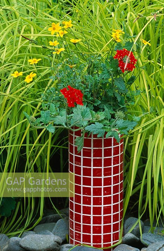 Red mosaic tube container planted with Bidens 'Yellow Breeze' and Verbena 'Sunmarisu'