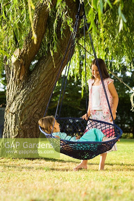 Two girls in garden, hanging seat under Weeping Willow 