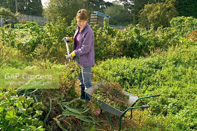 Making compost - lady forking vegetable waste