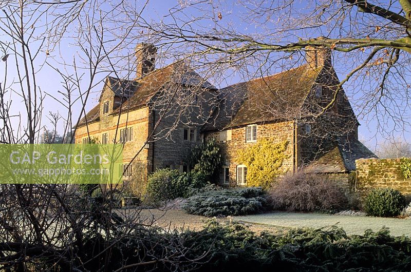 Frosty garden in winter with view of house - Coates Manor, Sussex 