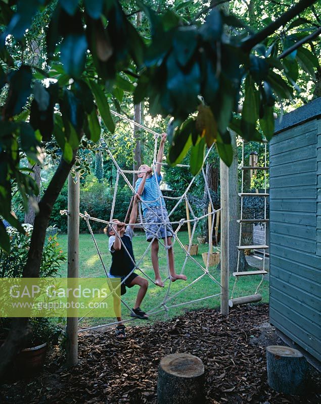 Spiders web rope climbing frame with young boys climbing on the web