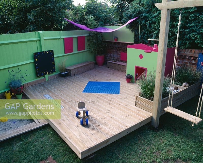 Childrens decking garden with raised bed with pebbles, shells, fir cones, crystals, gourds and vine balls
