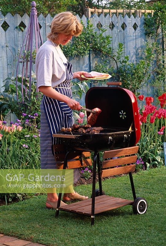 Woman cooking food on barbecue in the garden - Reading
