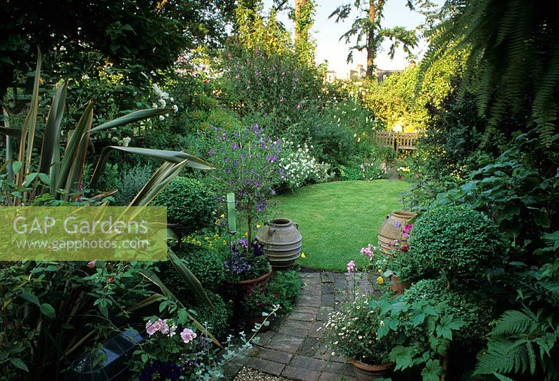 Brick path through cottage style planting to circular lawn area - London 