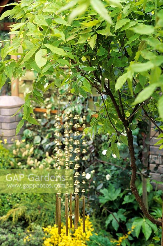 Metallic bell wind chimes hanging from tree in garden
