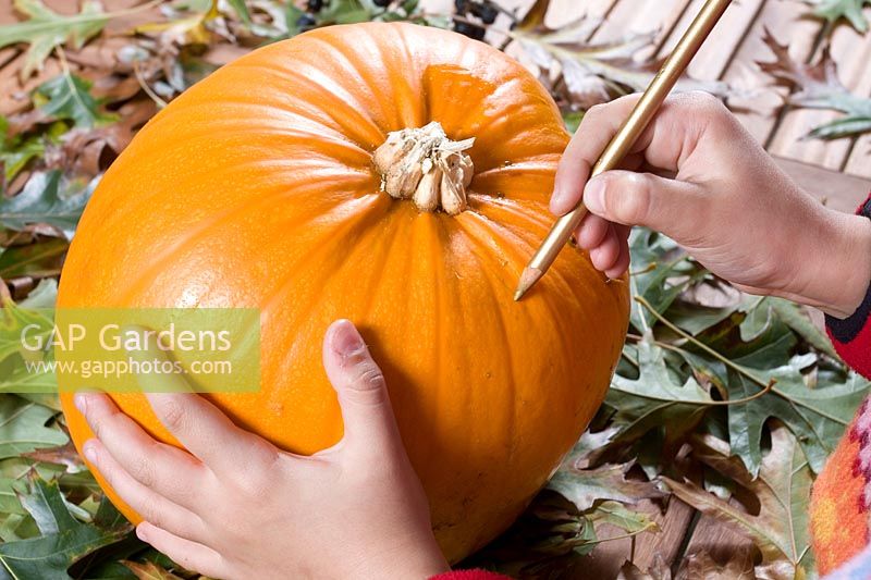 Girl drawing a face on pumpkin