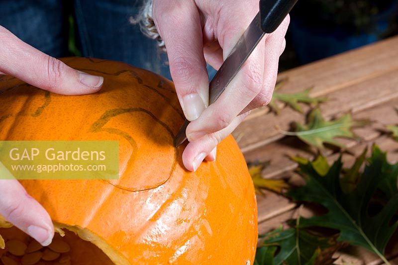 Cutting face with sharp knife from pumpkin, sequence of making Halloween lantern