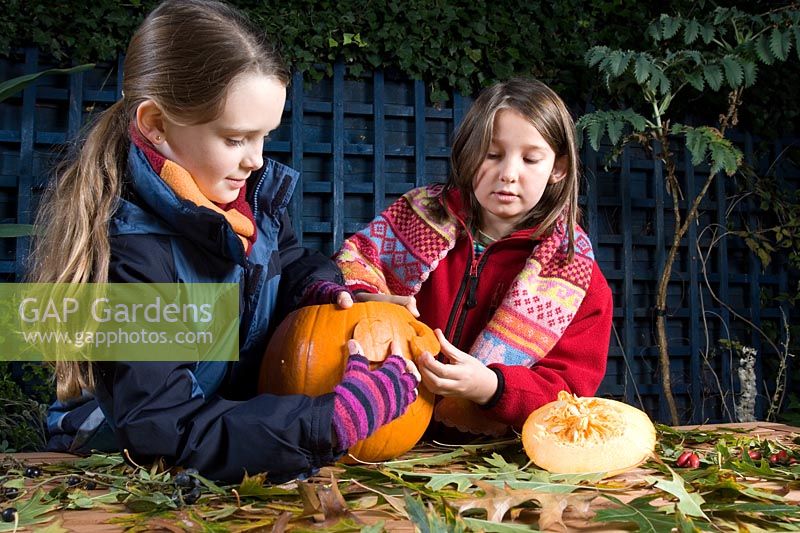 Girls removing eyes cut with sharp knife in pumpkin, sequence of making Halloween lantern