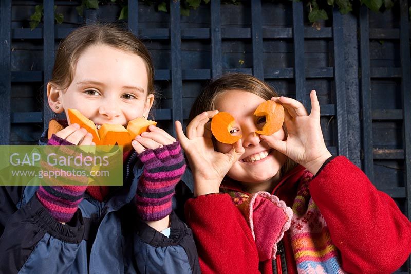Girls holding cut eyes and mouth from  Pumpkin, sequence of making Halloween lantern