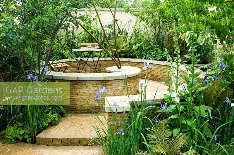 Curved dry stone wall, raised bed with Digitalis and Irises and wall mounted water feature - 'A City Haven' garden, Chelsea 2007