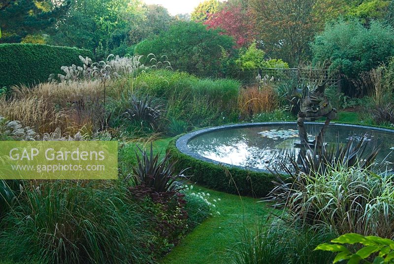 Dragon Garden with beds full of grasses  and central circular pond with dragon sculplture