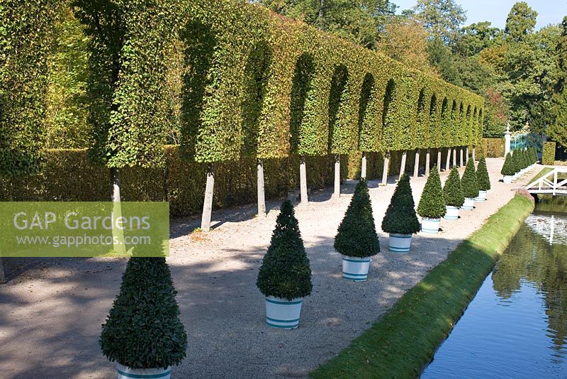 Canal running through the formal garden with orangery and topiary - Schwetzingen Schlossgarten, Germany 