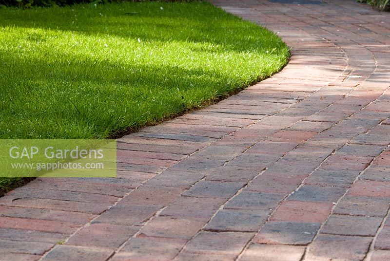 Winding Brick path with neatly edged lawn grass in May