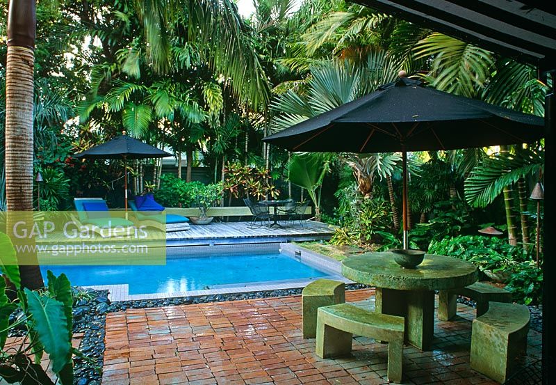 Courtyard walled garden with swimming pool, sun loungers, umbrellas, chairs and tables, and tropical planting - Key West, USA