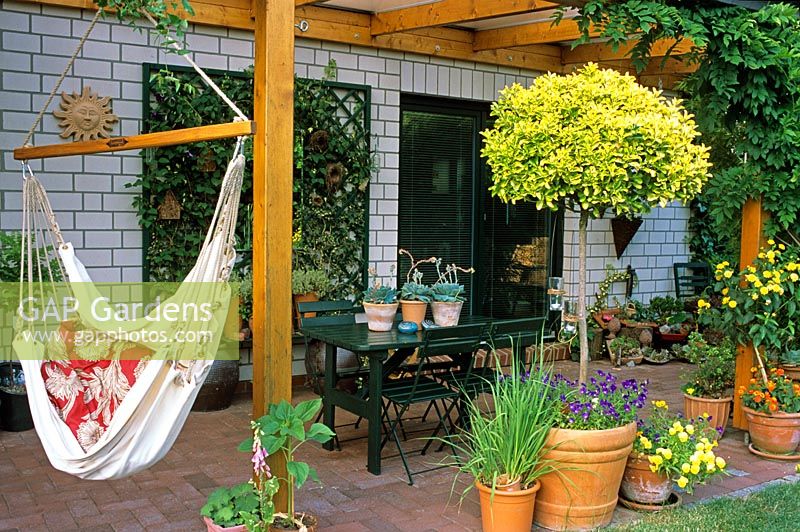 A summer terrace with a hammock and mixed plants in containers