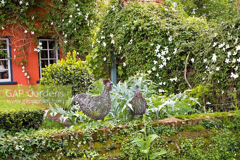 An informal cottage garden with ornamental hens on a wall