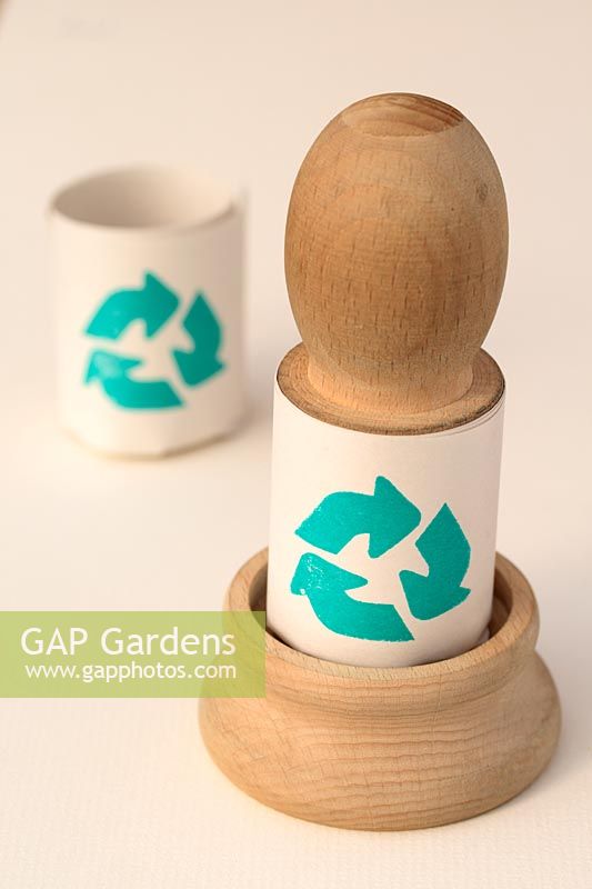 Wooden paper potter tool and a biodegradable newspaper pot with a recycling symbol