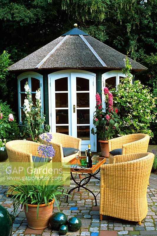 Rattan chairs and table on patio infront of summerhouse
