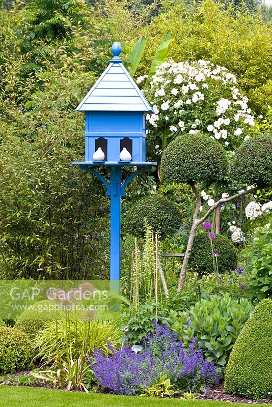 Blue wooden birdhouse in small country garden