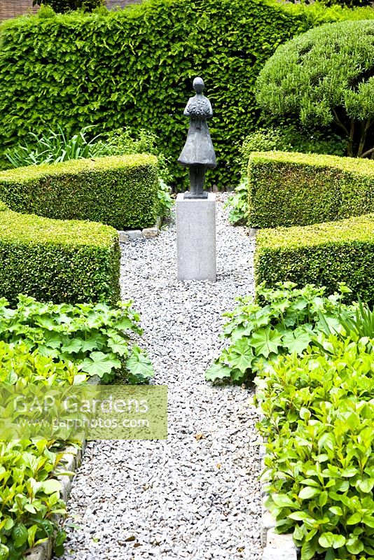 Formal garden with gravel paths and central figurative sculpture 