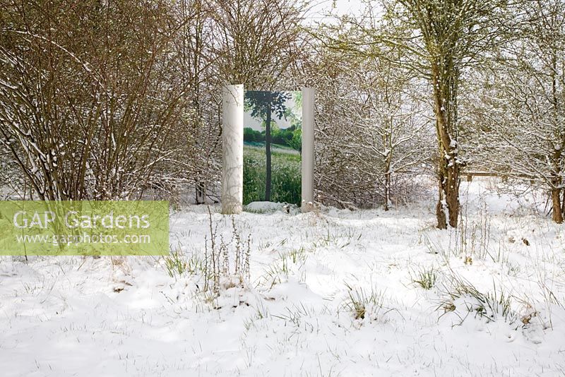 Contemporary stainless steel sculpture in a snow-covered meadow