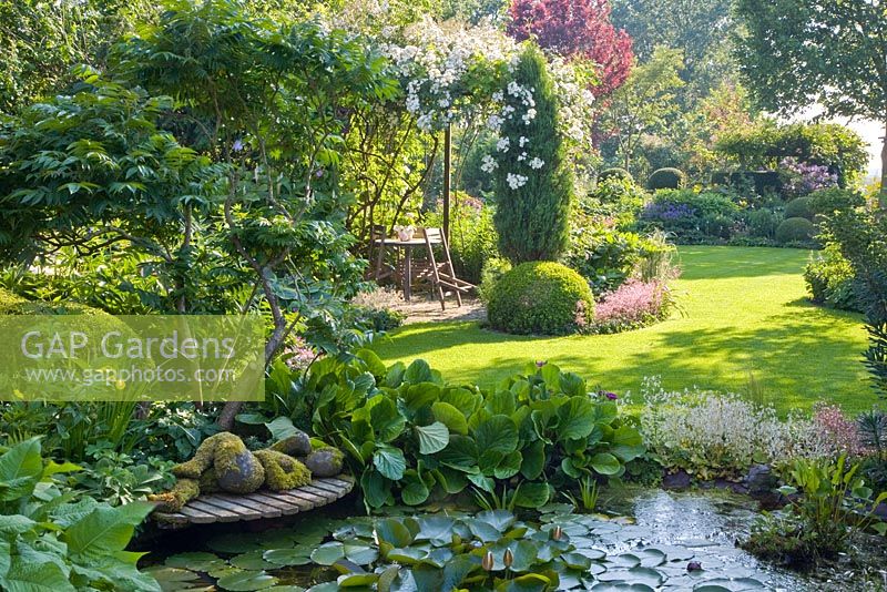 Pond in country garden with reclining sculpture on wooden decking
