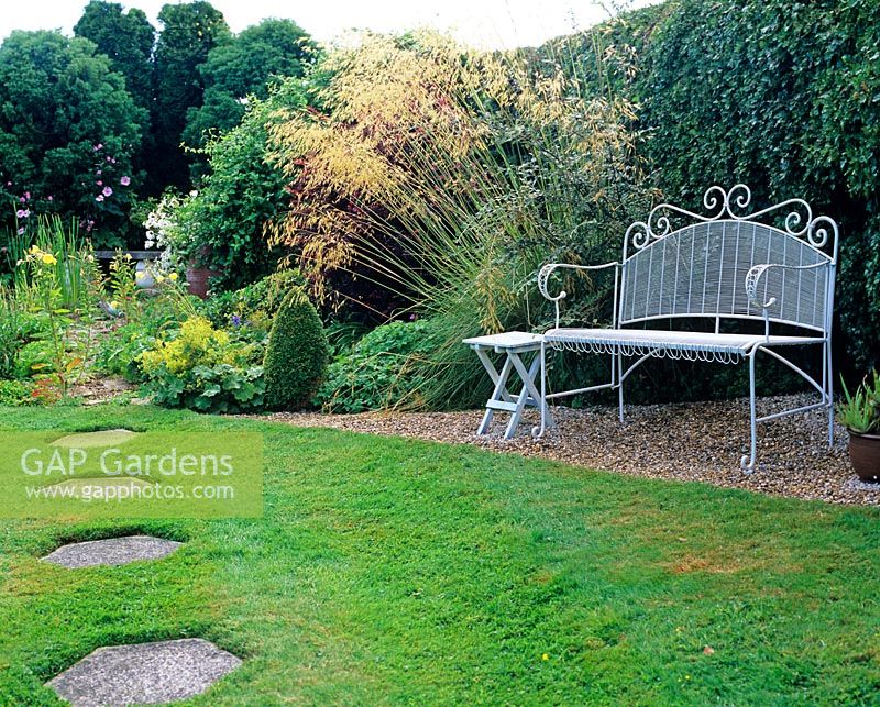 Bench by hedge and Stipa, hexagonal stepping stones in lawn