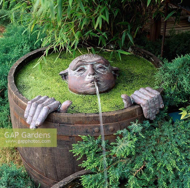 Half barrel water feature with submerged bronze head waterspout and hands
