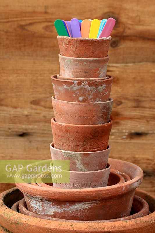 Stack of terracotta pots and coloured plastic labels in garden shed