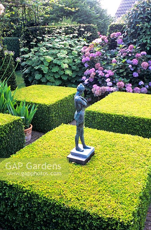 Sculpture in formal garden with clipped Buxus squares