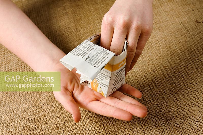 Making paper pots - Step 15 - With point facing table, insert fingers into the open end and pull