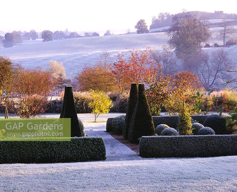 View across parterre to open countryside with ridge and furrow field in frost - Pettifers Garden, Oxfordshire