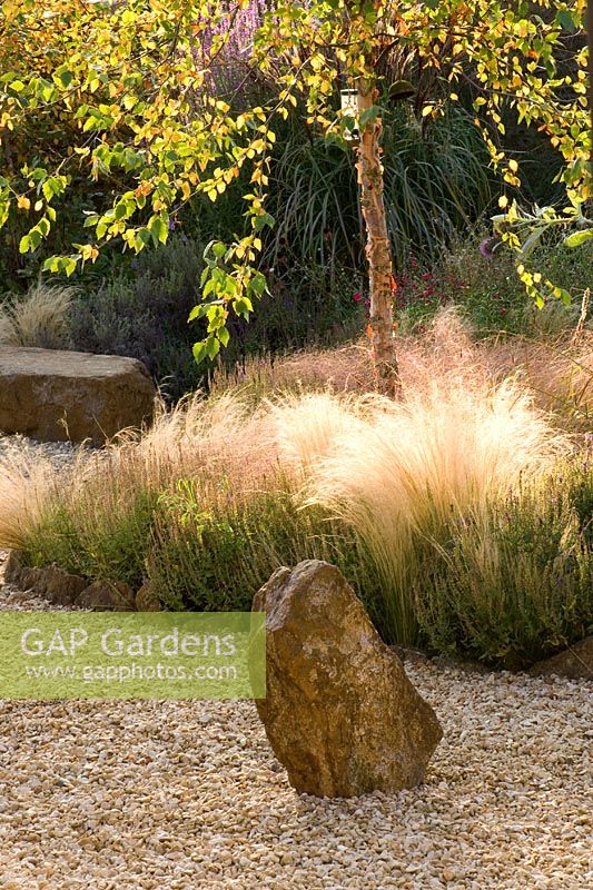 Gravel garden with bed of Stipa tenuissima, rock sculpture and rock seat 