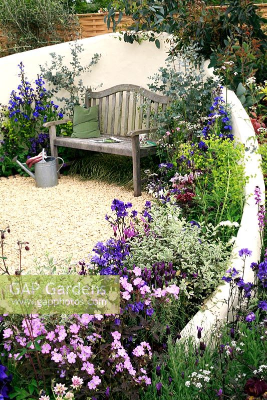 A curved, rendered wall encloses a seat and provides a backdrop to colourful perennials