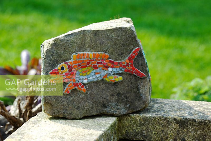 A brightly coloured, small fish mosaic on a rock 