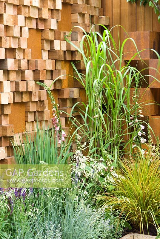 Mixed grasses and perennials with a wall created from irregular wooded blocks inlaid with corten steel - Garden - The Pemberton Greenish Recess Garden, Designer - Paul Hensey with Knoll Gardens Sponsor - Pemberton Greenish