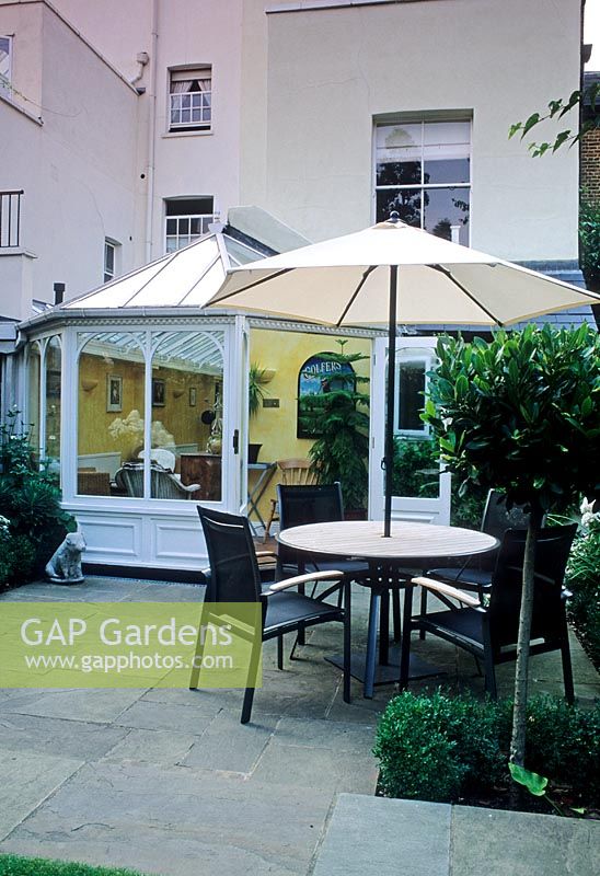 Small urban garden with table, chairs and parasol on paved area