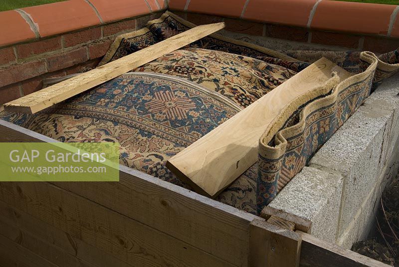 Use of old rug to cover compost in purpose built bay