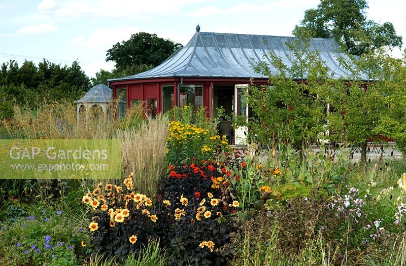 Red cafe building surrounded by late summer perennial border planting - Harvey's Garden Plants, Thurston, Suffolk