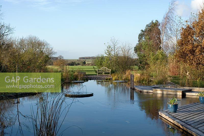 Natural swimming pool with wooden decking and mill stone fountains in November