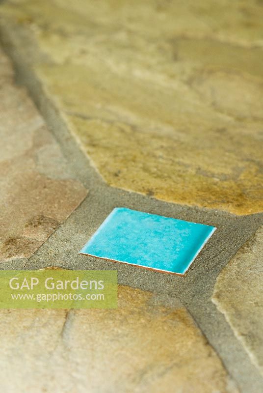 Decorative turquoise glazed tile inset into stone paving