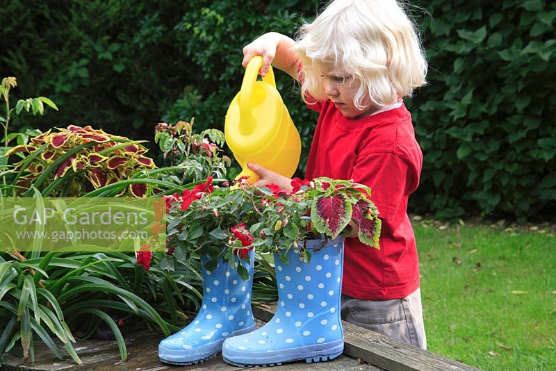 Young child girl in garden watering plants